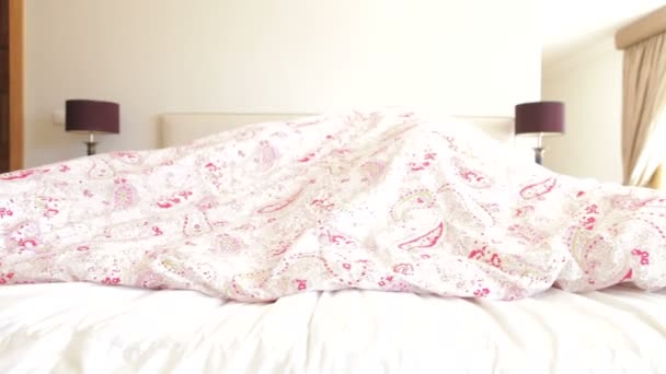 Старшая пара прячется под одеялом на кровати — стоковое видео
