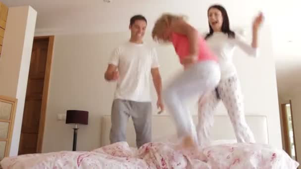 Jong meisje stuitert opgewonden op bed met ouders. — Stockvideo