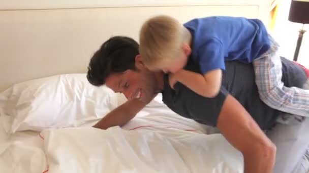 Vater gibt Sohn auf Rücken, bevor er ihn ins Bett kippt. — Stockvideo