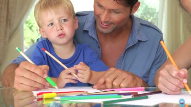 Padre ayudando a su hijo mientras la cámara se acerca a la madre y la hija trabajando en la foto con bolígrafos juntos . — Vídeos de Stock