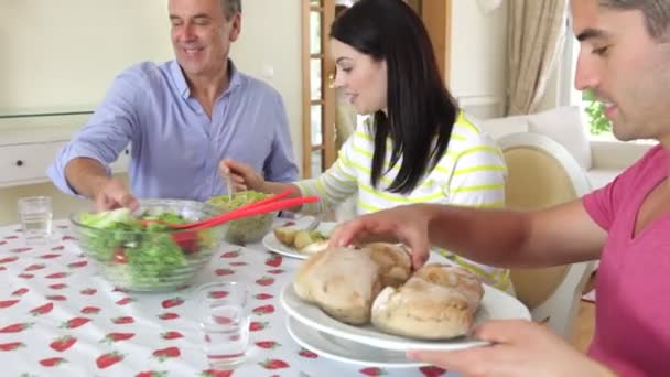 Parejas sentadas alrededor de la mesa de comedor sirviendo comida . — Vídeo de stock