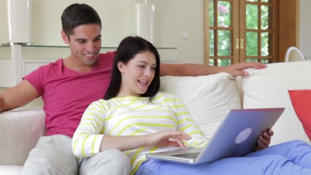 Couple heureux relaxant sur canapé avec ordinateur portable . — Video