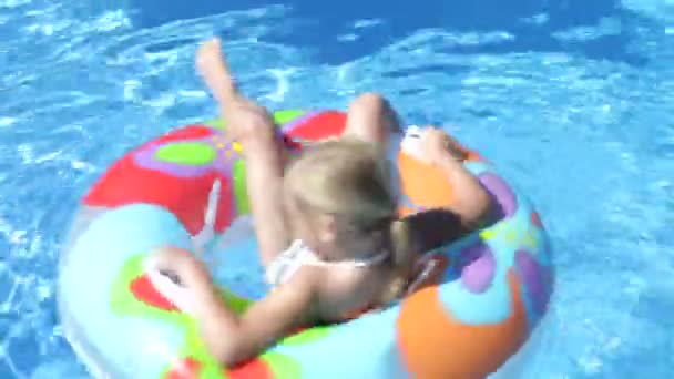 Meisje liggend op opblaasbare rubberring drijvend in zwembad en draaien. — Stockvideo