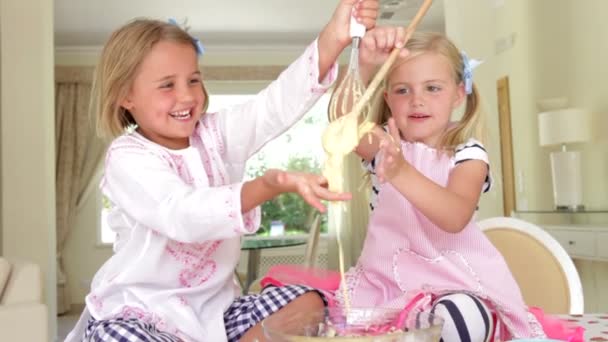 Twee meisjes taart mengsel uit kom proeven — Stockvideo