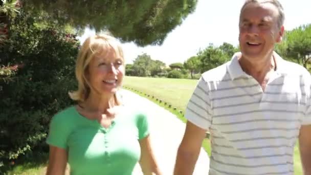 Romantische senior paar hand in hand als ze langs land pad lopen. — Stockvideo