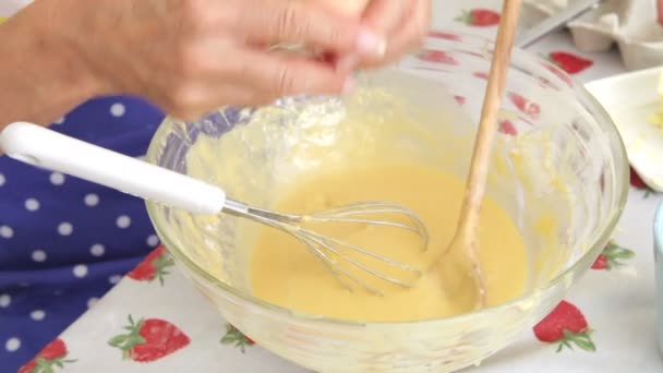 Senior woman breaking egg into bowl and then whisking into mixture. — Stock Video