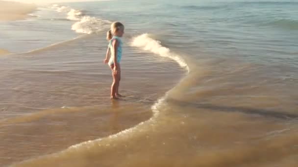 Jong meisje weglopen van golven als ze op de kust breken. — Stockvideo