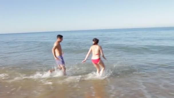 Casal correr para o mar antes de espirrar um ao outro . — Vídeo de Stock