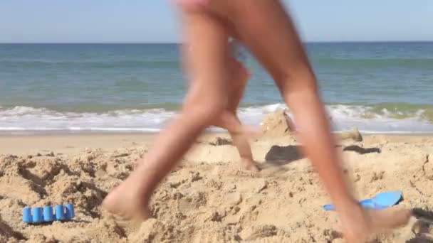 Две молодые девушки бегают вокруг дыры в песке, прежде чем прыгать в . — стоковое видео