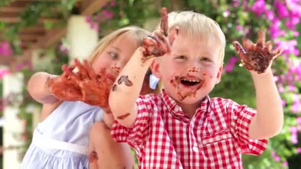 Kinderen zitten aan tafel chocolade overdekte handen zwaaien — Stockvideo