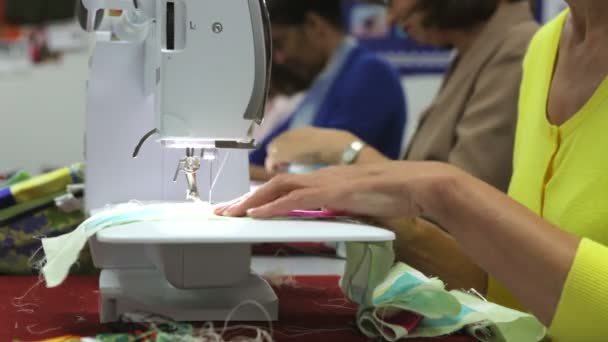 Жінка годує матеріал за допомогою швейної машини . — стокове відео