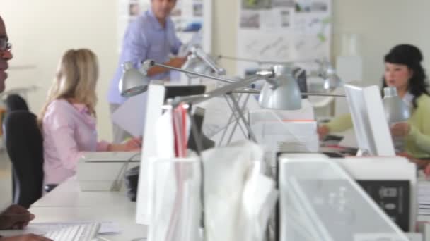 Twee kantoorpersoneel discussie hebben aan bureau met collega's op achtergrond. — Stockvideo