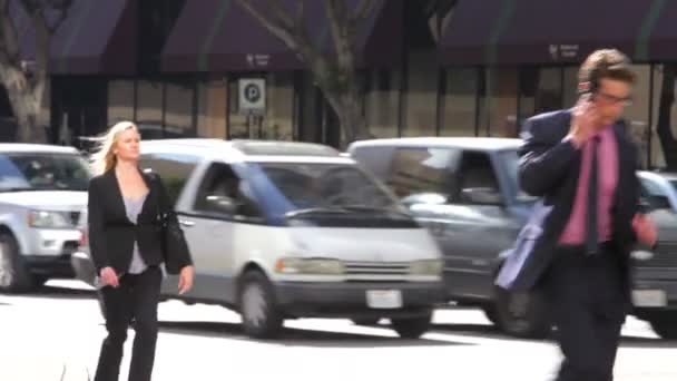 Young businessman rushing and talking on mobile phone to older businessman walking along and smiling. — Stockvideo