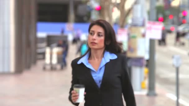 Businesswoman holding cup of takeaway coffee walks into and then out of frame. — Stock Video