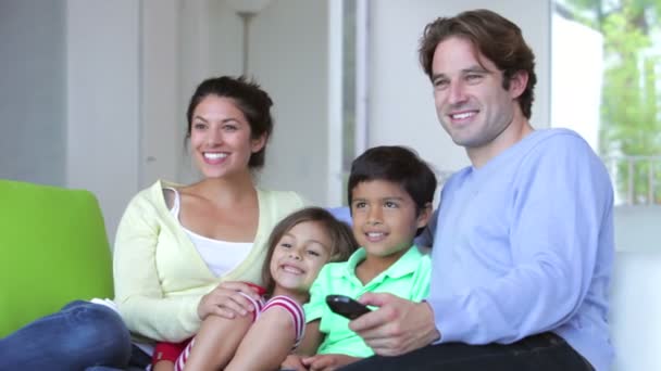Семья из четырех человек сидит на диване — стоковое видео