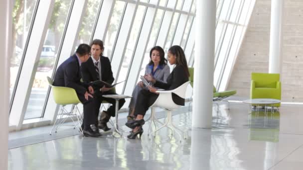 Businesspeople sit and have informal meeting discussing report and using digital tablet together. — Stock Video