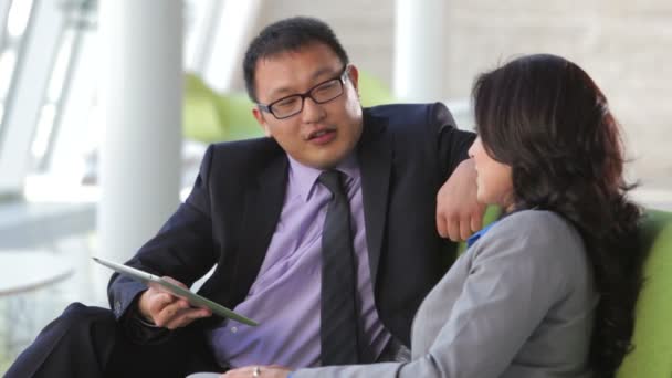 Businesspeople sit and have informal meeting looking at data on digital tablet together. — Stock Video