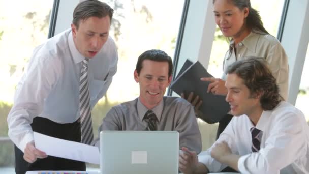Vier Geschäftsleute sitzen zusammen und treffen sich beim Blick auf den Laptop. — Stockvideo