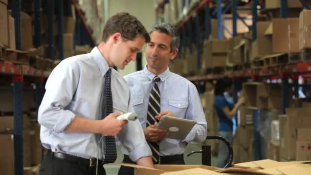 Two businessmen checking contents of boxes using digital tablet and hand held scanner. — Stock Video