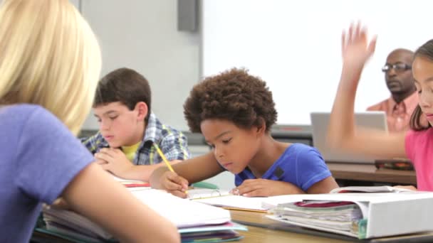 Schüler, der am Schreibtisch arbeitet, hebt die Hand, um Lehrerfrage zu stellen — Stockvideo