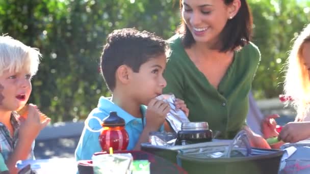 Barn äta sin matsäck som övervakas av lärare — Stockvideo