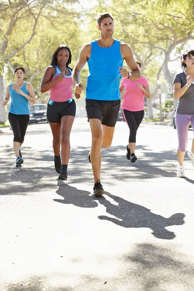 Grupo de mujeres corriendo a lo largo de la calle con entrenador personal — Foto de Stock