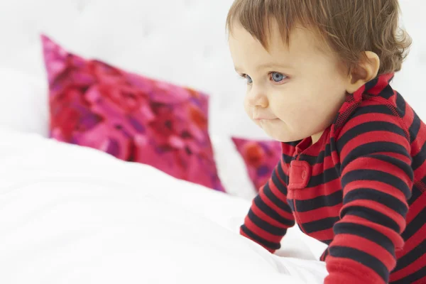 Criança rastejando na cama vestindo pijamas — Fotografia de Stock