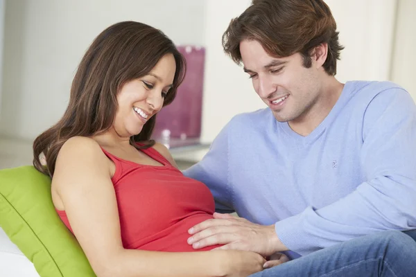 Мужчина отдыхает на диване с беременной женой дома — стоковое фото