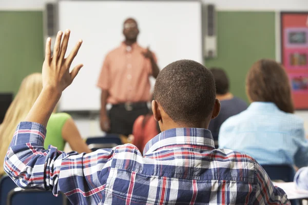 Aluno masculino levantando a mão na classe — Fotografia de Stock