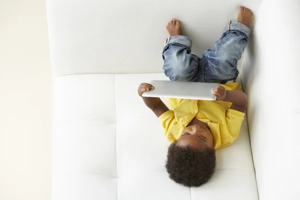 Översiktsbild av pojke på soffa leker med digital tablet — Stockfoto