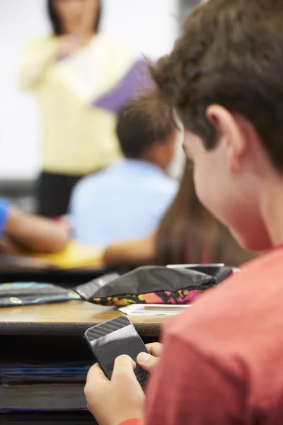 Alumnos enviando mensajes de texto en el teléfono móvil en clase — Foto de Stock