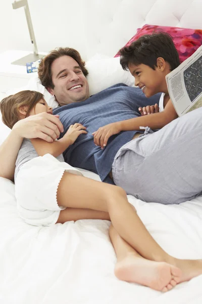 Far och barn slappar i sängen tillsammans — Stockfoto