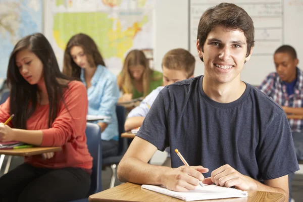 Porträt eines männlichen Schülers, der am Schreibtisch im Klassenzimmer lernt — Stockfoto