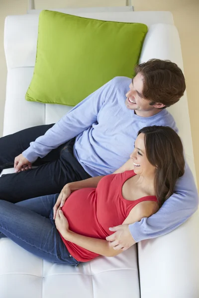 Visão aérea do homem assistindo TV no sofá com esposa grávida — Fotografia de Stock