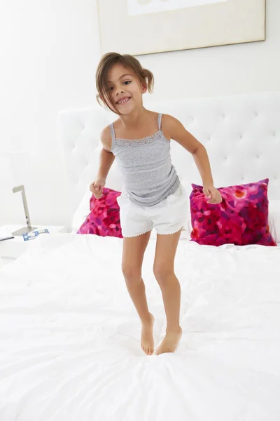 Mädchen springt im Schlafanzug aufs Bett — Stockfoto
