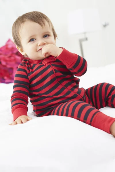 Yürümeye başlayan çocuk pijama giymiş yatağın üstüne oturuyor — Stok fotoğraf