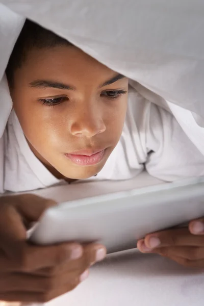 Jongen met behulp van digitale Tablet PC onder dekbed — Stockfoto