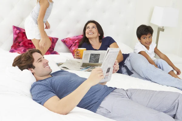 Familie ontspannen in bed met koffie en krant — Stockfoto