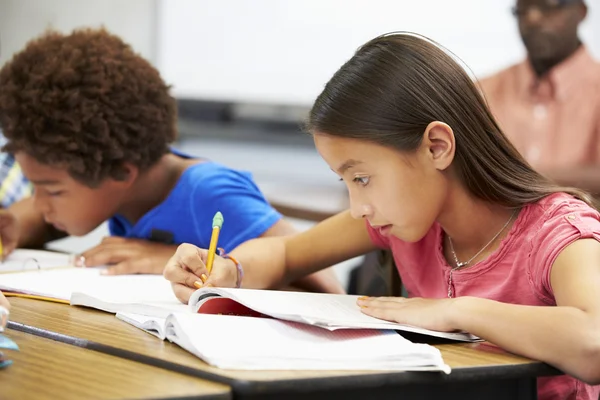 Leerlingen studeren aan bureaus in klas — Stockfoto