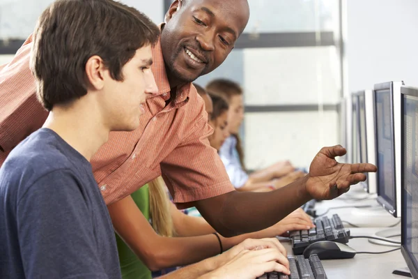 Profesor ayudando a los estudiantes a trabajar en computadoras en el aula — Foto de Stock