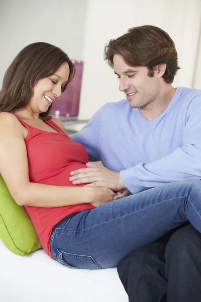 Man koppla av på soffan med gravida hustru hemma — Stockfoto