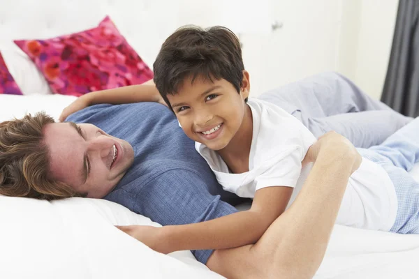 Padre e hijo acostados en la cama juntos — Foto de Stock