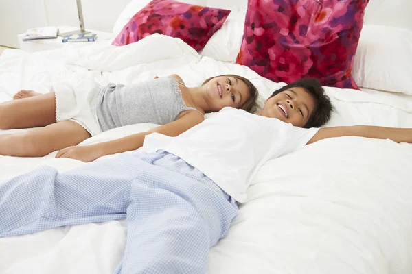Дети, лежащие на кровати в пижаме вместе — стоковое фото