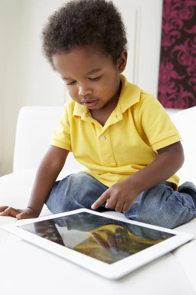 Glücklicher Junge auf dem Sofa, der mit digitalem Tablet spielt — Stockfoto