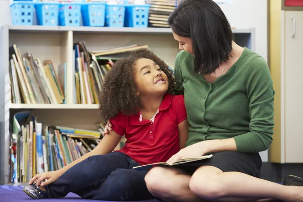 Elementaire leerling lezen met leraar in de klas — Stockfoto