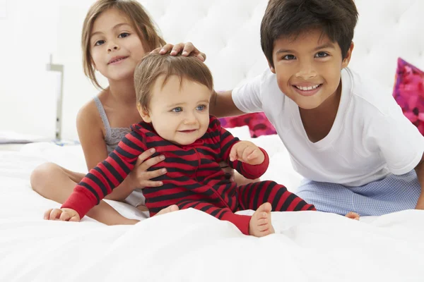 Kinder sitzen gemeinsam im Schlafanzug auf dem Bett — Stockfoto