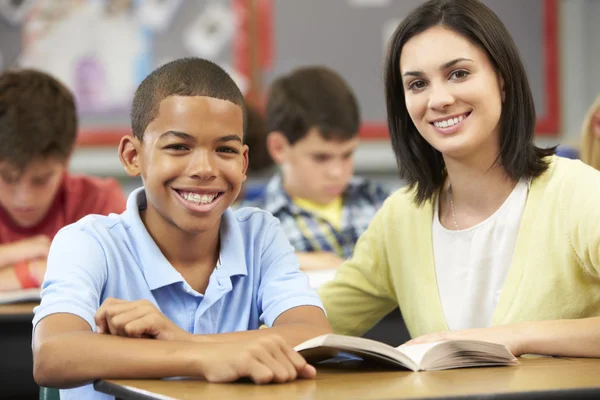 Lärare som läser med manlig elev i klass — Stockfoto