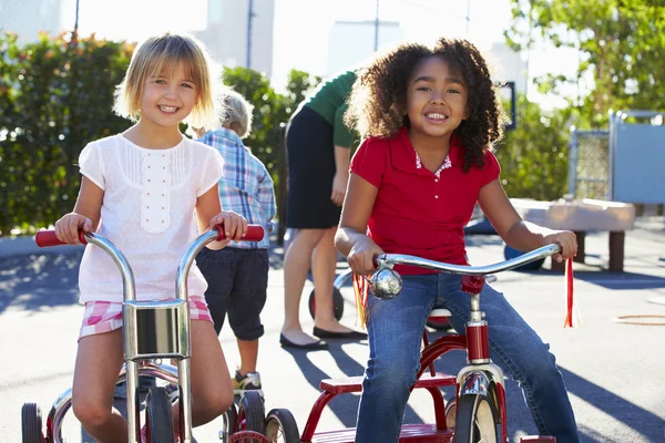 Duas meninas equitação triciclos no parque infantil — Fotografia de Stock