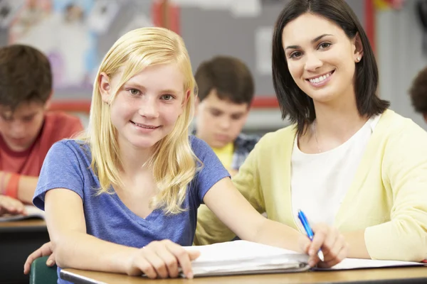 Lehrer hilft Schülern beim Lernen am Schreibtisch im Klassenzimmer — Stockfoto