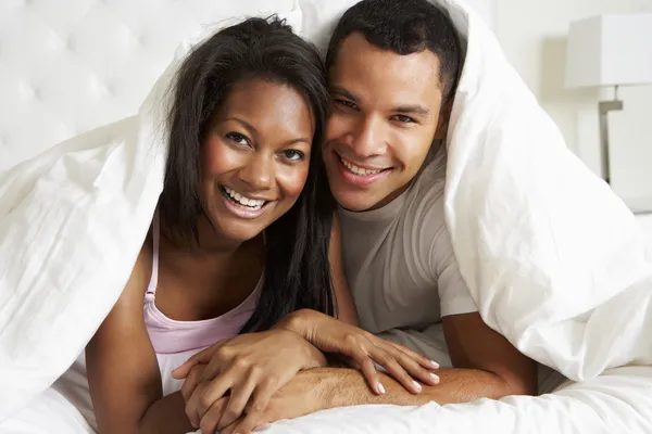 Casal relaxante na cama escondido sob edredão — Fotografia de Stock